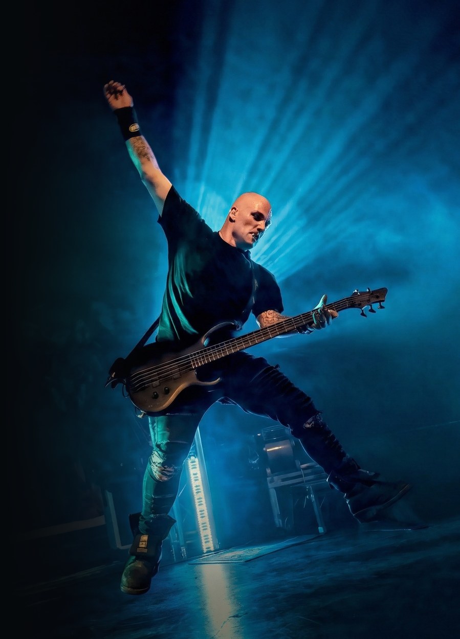 Dean mid-air on stage with his bass, fist raised
