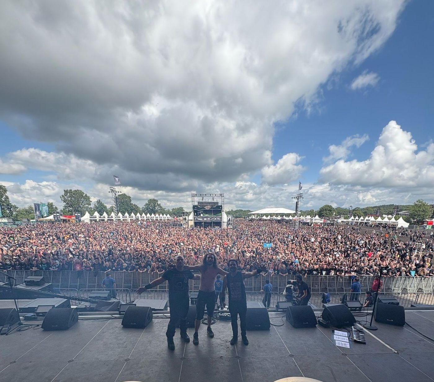 The same festival stage during the set: a packed field from behind the drum kit