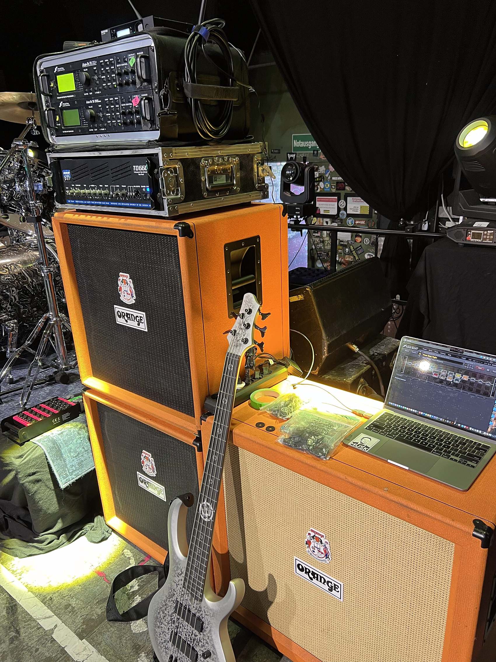 The full rig stage left: rack on top of two Orange bass cabinets, a five-string bass leaning against them